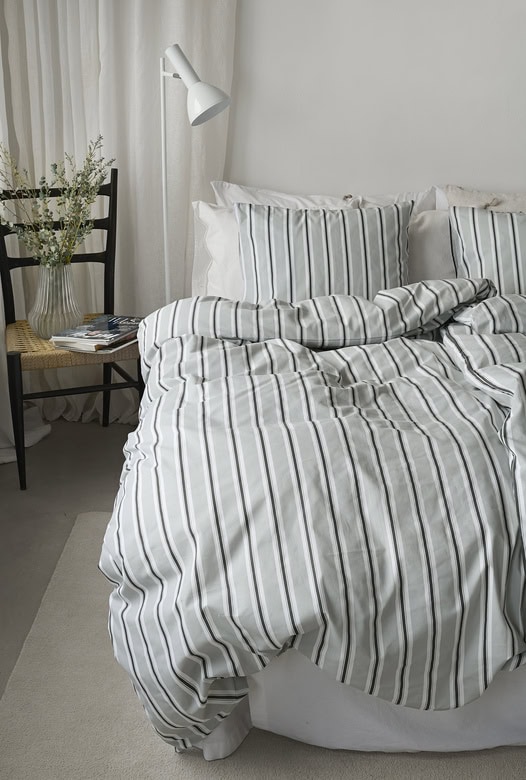 1. Sängkläder i linne med vit- och grårandig design för sovrum inredning.
