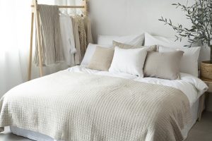 Hälsosöm och stilren säng med vita och beige textilier för ett behagligt sovrum.
