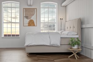 Ljust sovrum med stilrent sänggavel och stora fönster med utsikt.