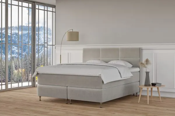 Ljust sovrum med modern säng och stor panoramafönster mot snötäckta berg.