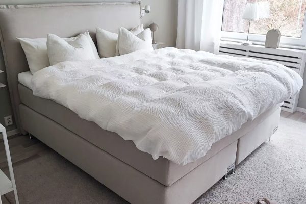 Ljust sänggavel i ljusgrått, perfekt för skandinavisk stil och komfort.