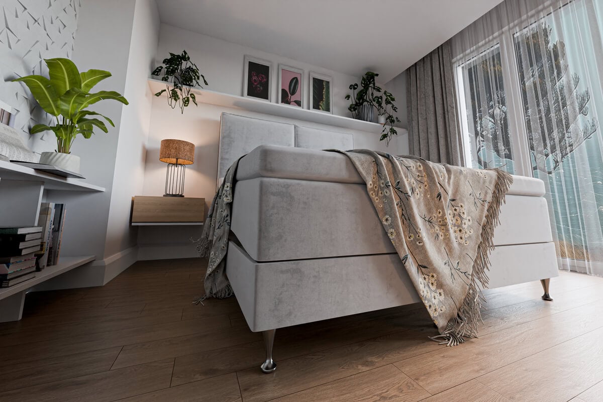 Säng med vit sängram och dekorativa textilier i ett modernt sovrum.