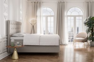 Elegant sovrum med stående fönster, bekvämt sänggavel och ljusa gardiner, perfekt för avkoppling.