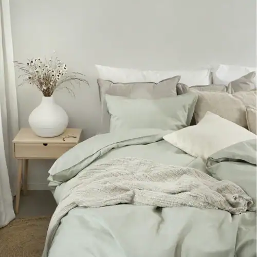 Elegant sängtäcke och kuddar i naturliga färger för en mysig sovmiljö.