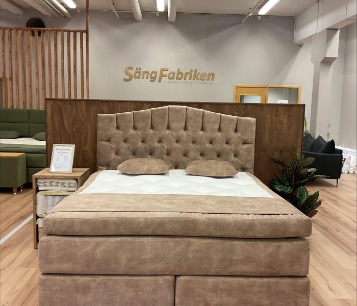 Ljus och modern säng med komfortabel tuftad huvudgavel i showroom.