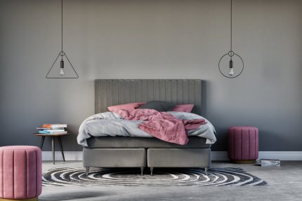 Modern säng med grått huvudgavel och rosa och mörkgrå sängkläder.