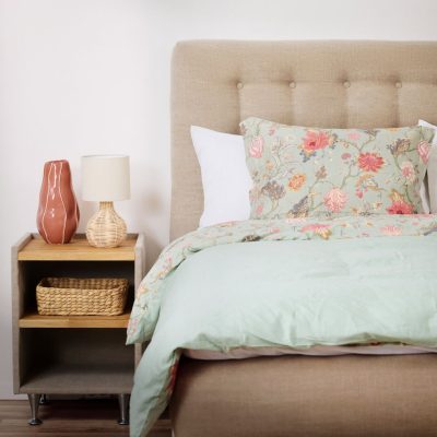 Möblerad säng med sängkläder och nattbord med dekorativa element, perfekt för sovrum inredning.