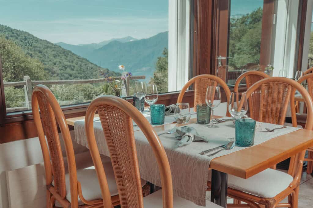 Dining room at Sass da Grüm restaurant with wooden tables and chairs overlooking Lago Maggiore