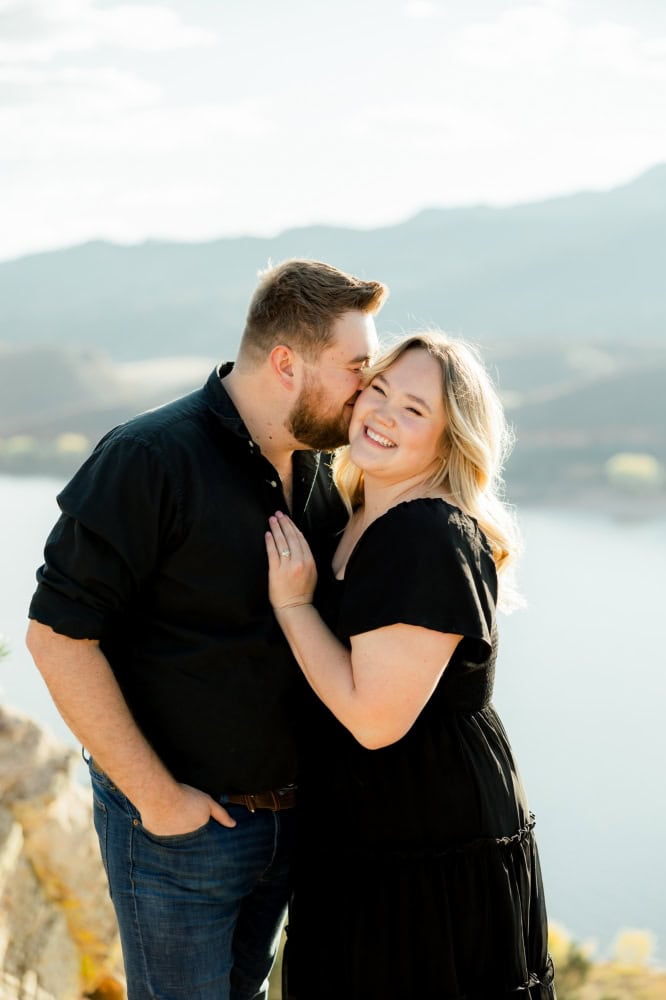 Couple cuddling into each other and smiling during their engagement session at Horsetooth in Fort Collins