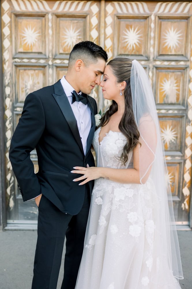 Bride and groom standing forehead to forehead in front of unique double doors