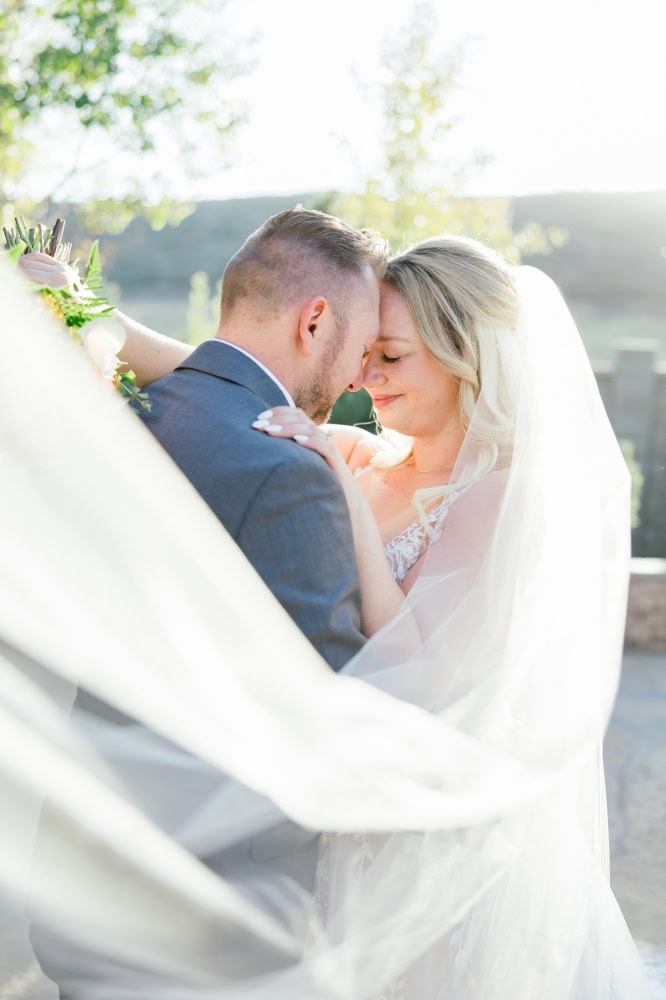 Bride and groom forehead to forehead with veil flowing in front of them