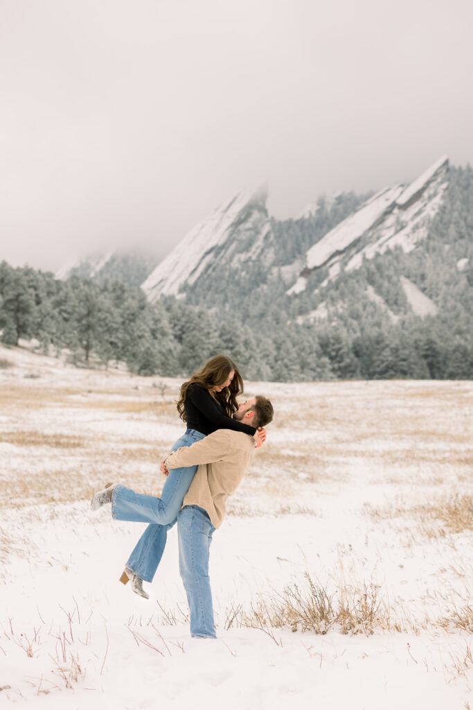 Couple laughing as he lifts her into the air during engagement session at Chautauqua Park in Boulder Colorado