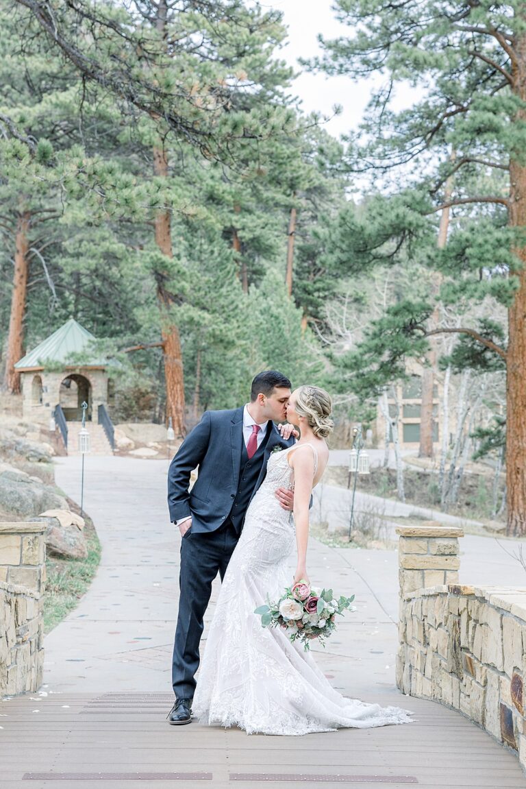 Bride and Groom kissing over top a bride with pine tree backdrop