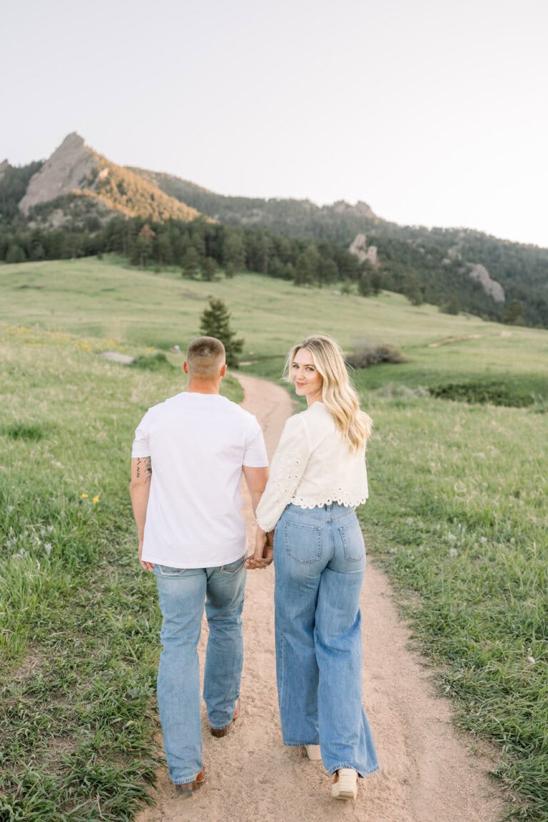 Couple walking on dirt path while girl is smiling over her shoulder