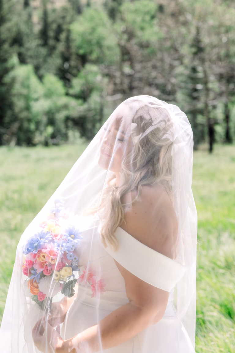 Bride gazing up towards the sun with veil over her face
