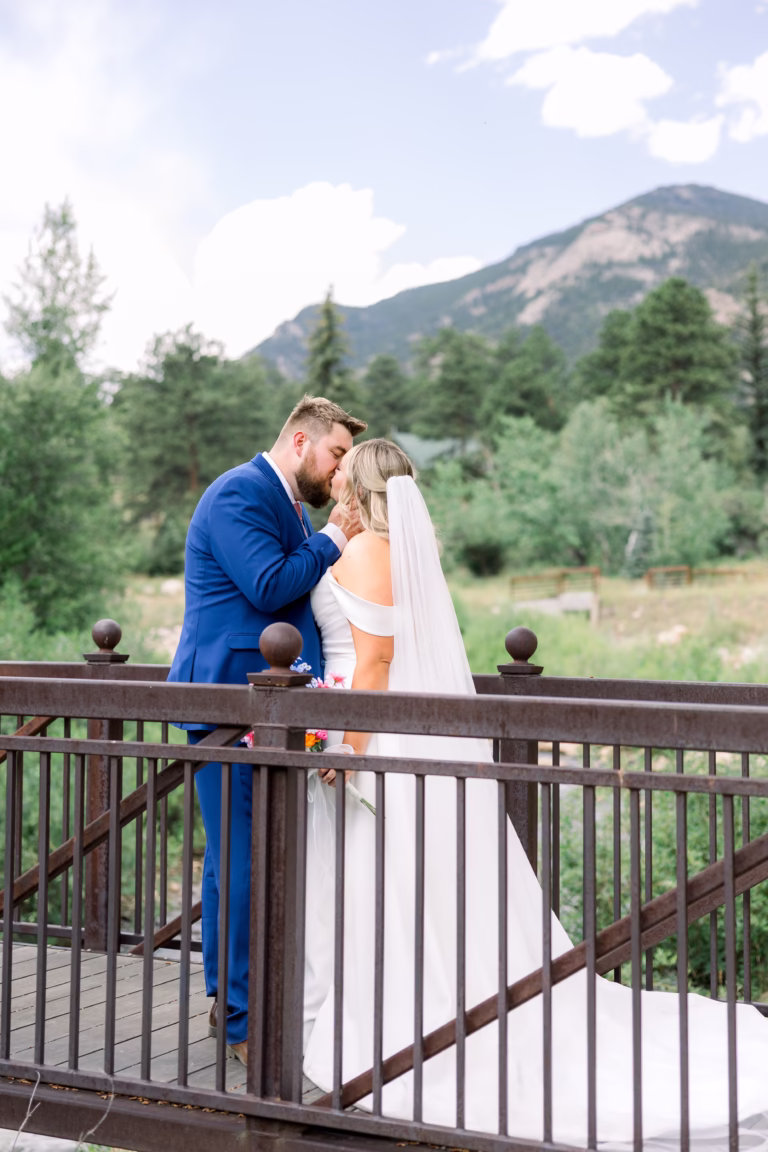 Bride and Groom sharing kiss on a bride with river and mountains in the background