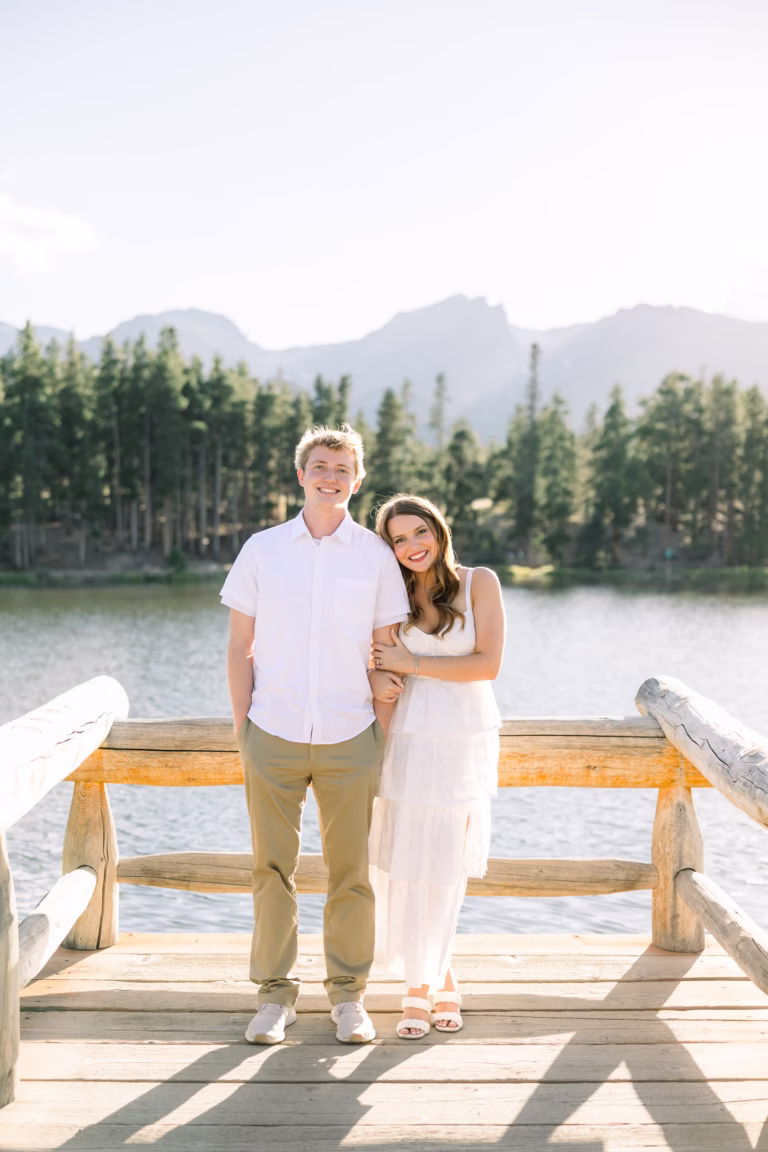 couple standing on a bridge smiling at camera
