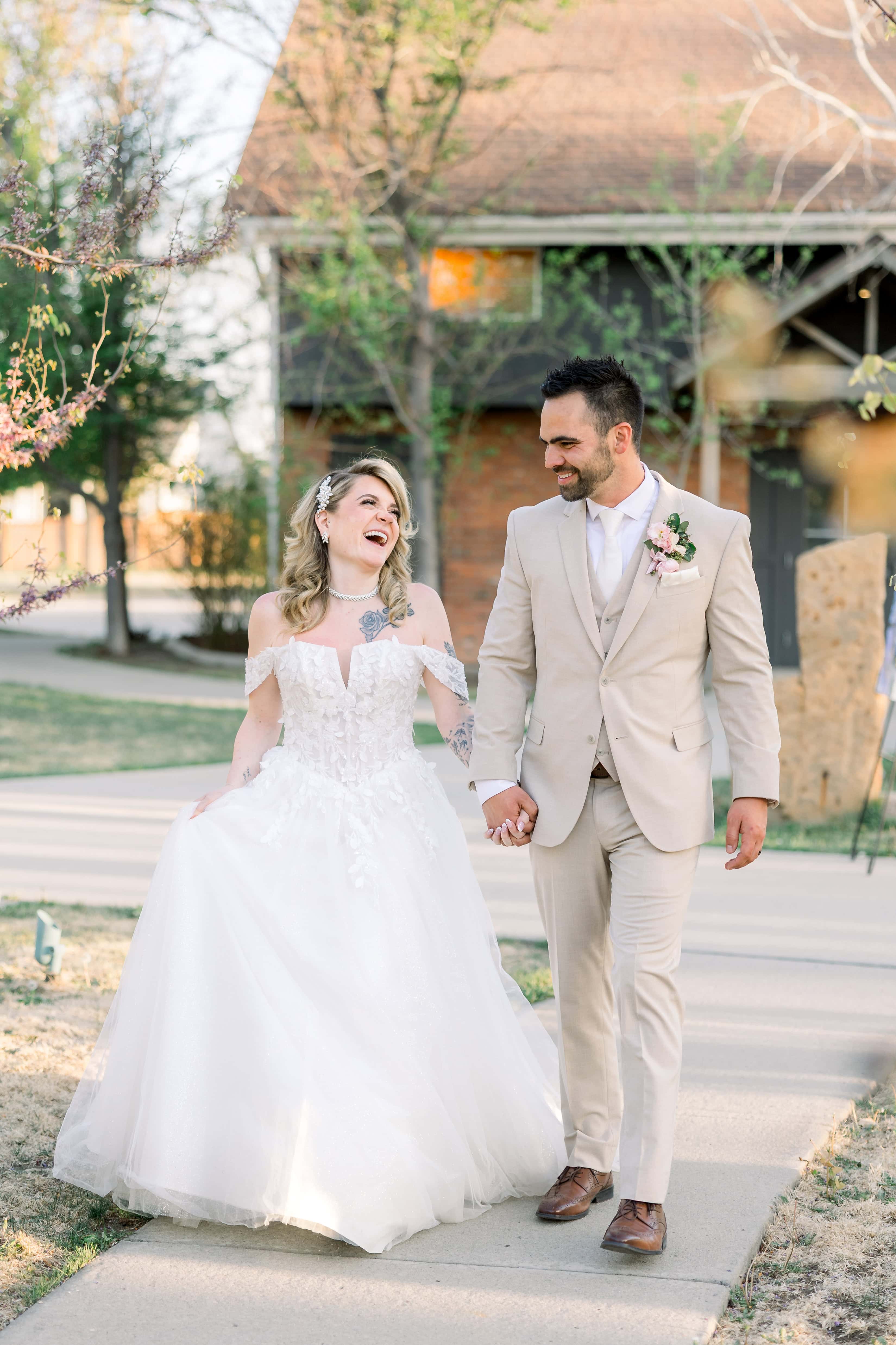 bride and groom walking in garden laughing