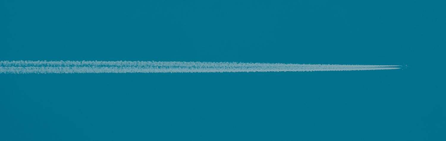 Airplane flying through a blue sky with a white contrail