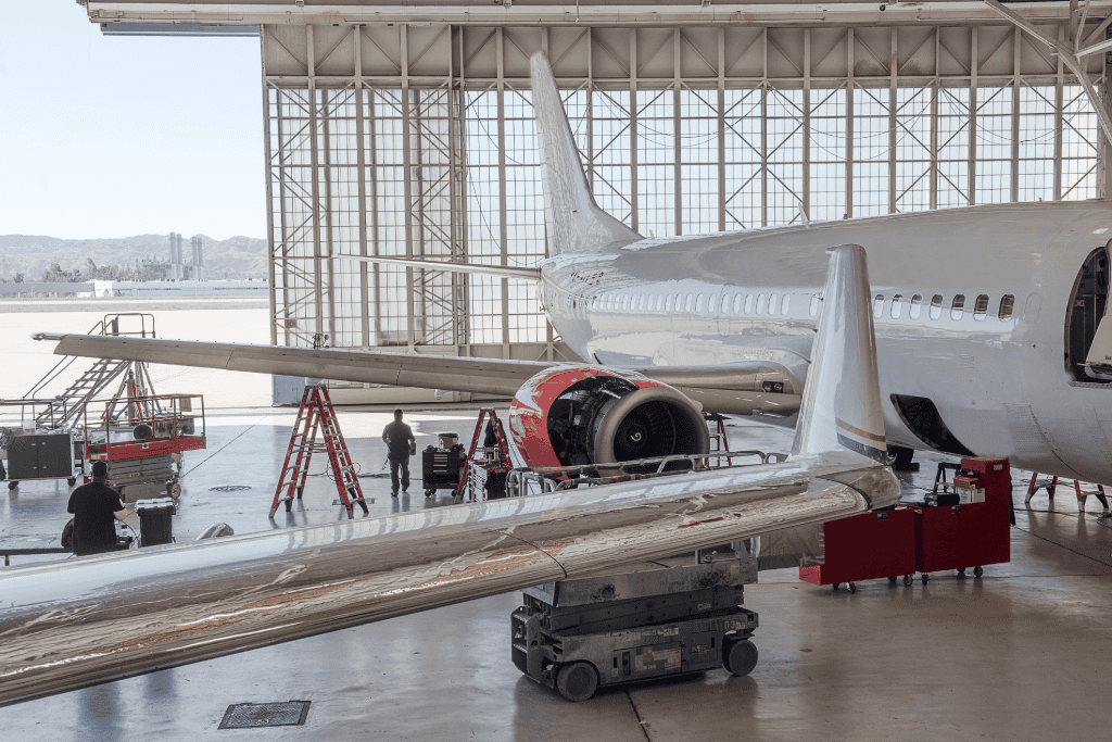 A photo of a maintenance repair and overhaul hangar with aircraft, tools and a aircraft mechanic