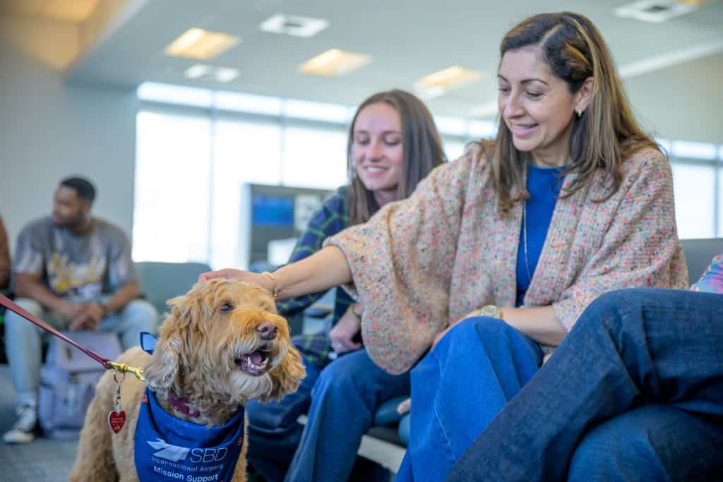Two women petting an emotional support dog in an airport terminal