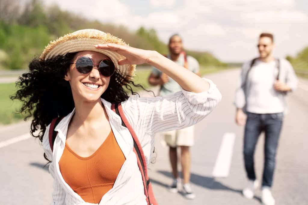Cool millennial lady with multiracial friends a having fun summer journey, exploring the outdoors