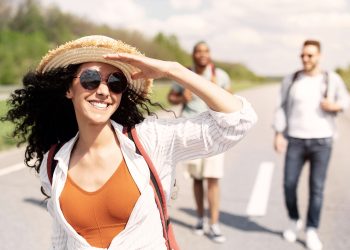 Cool millennial lady with multiracial friends a having fun summer journey, exploring the outdoors