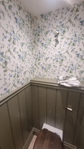1. Traditional floral wallpaper in a bathroom with wood paneling and modern fixtures.