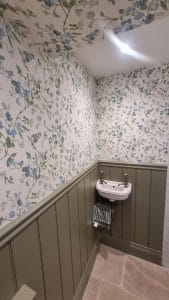 1. Floral wallpaper in a bathroom with wooden paneling and small sink for interior design.