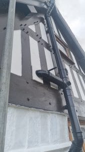 Black gutter and pipe installation on traditional black and white half-timbered house.