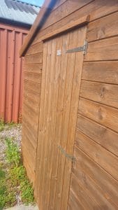 Natural wooden garden shed with durable cladding and secure door, expertly painted by S Bond Decorating.