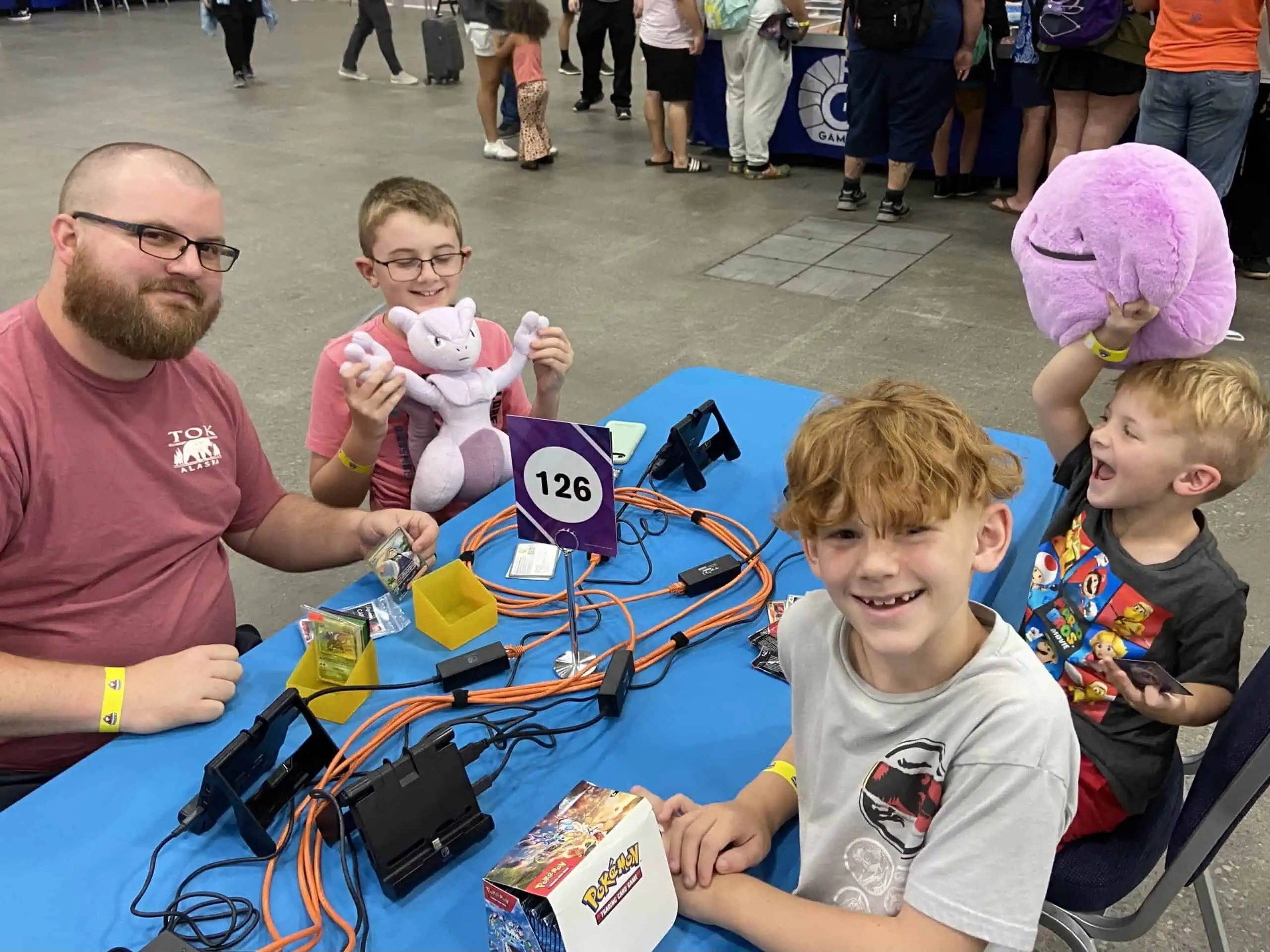 A man and two children sitting at a table with a stuffed animal.