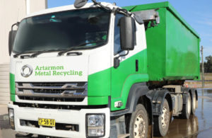 Green and white scrap metal recycling truck at weigh and pay station.