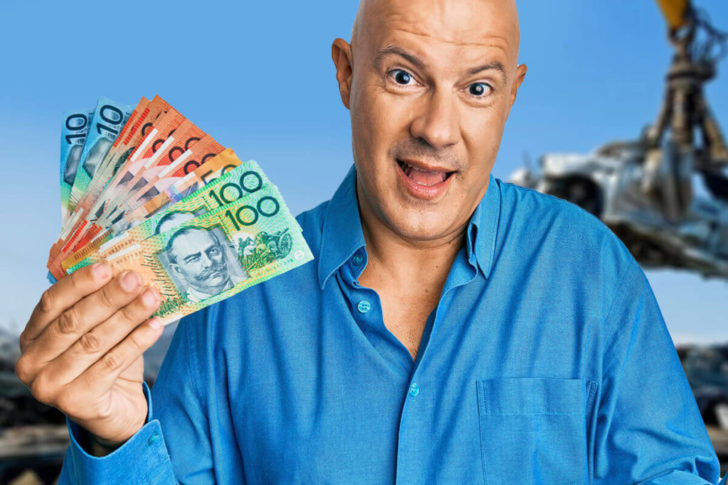 Man holding Australian dollar notes with recycling yard in background.