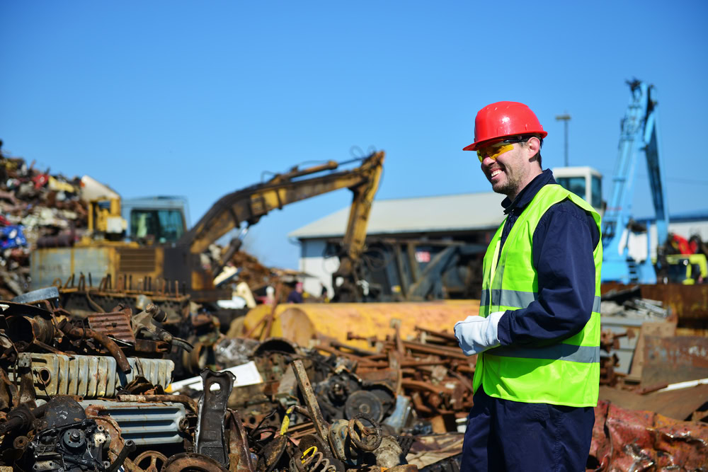 Scrap metal worker inspecting metal scrap at recycling yard in Australia.
