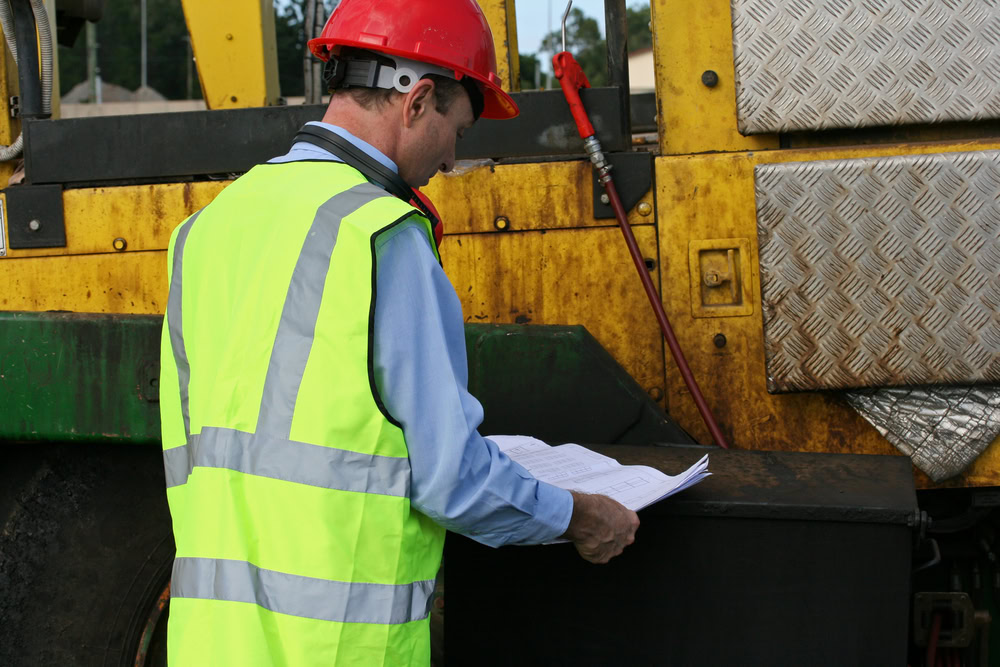 Worker inspecting scrap metal bins for recycling and waste management.