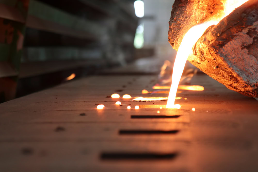 Molten cast iron being poured into a mold for scrap metal recycling.
