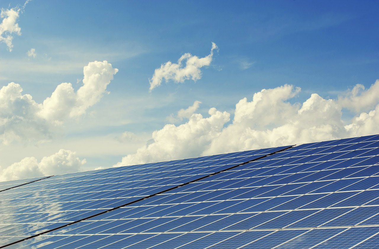 Solar panels on a blue sky with clouds, highlighting solar panel recycling efforts.