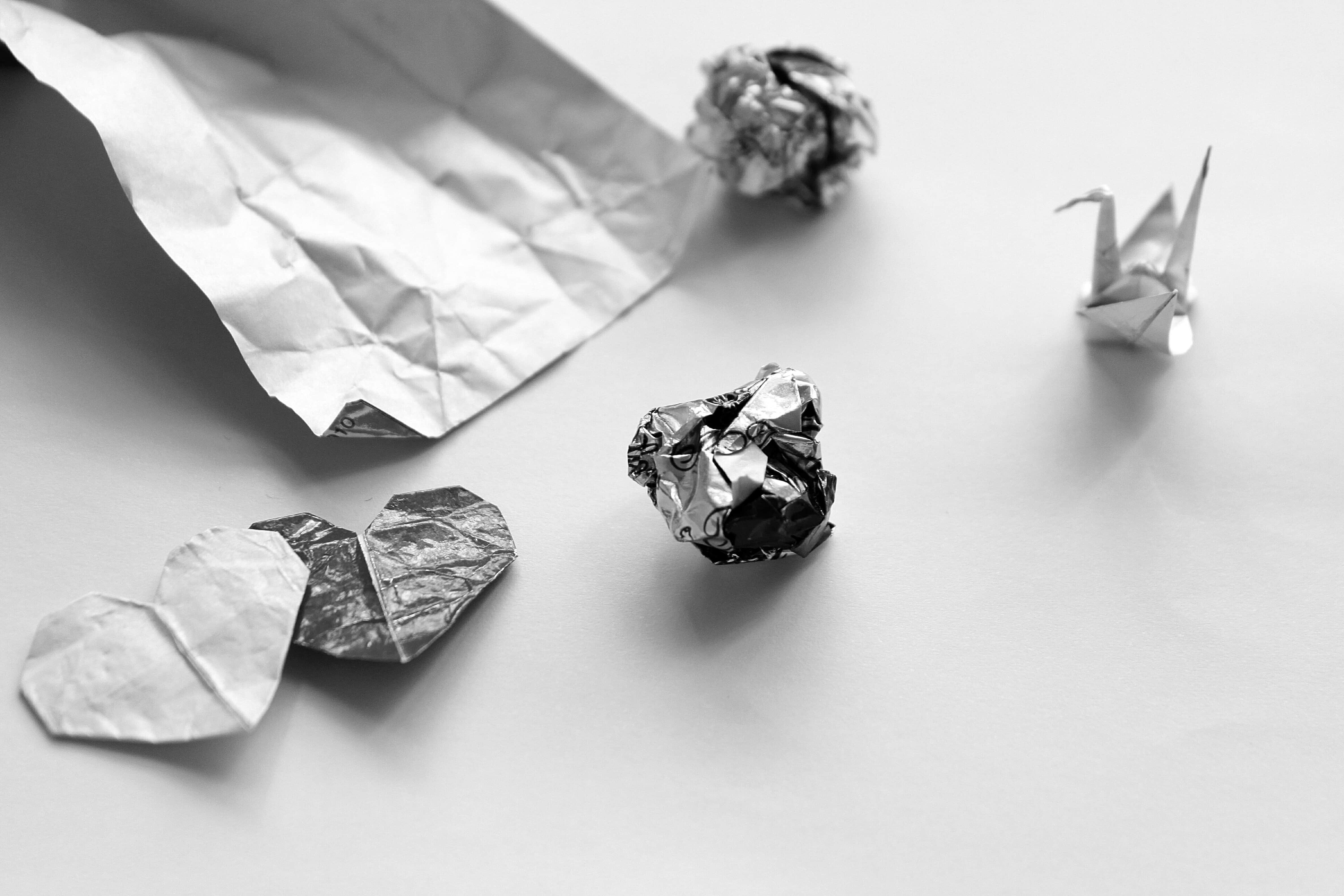 Alttext: Zerknautschtes Papier und Origami-Tier auf weißem Hintergrund.