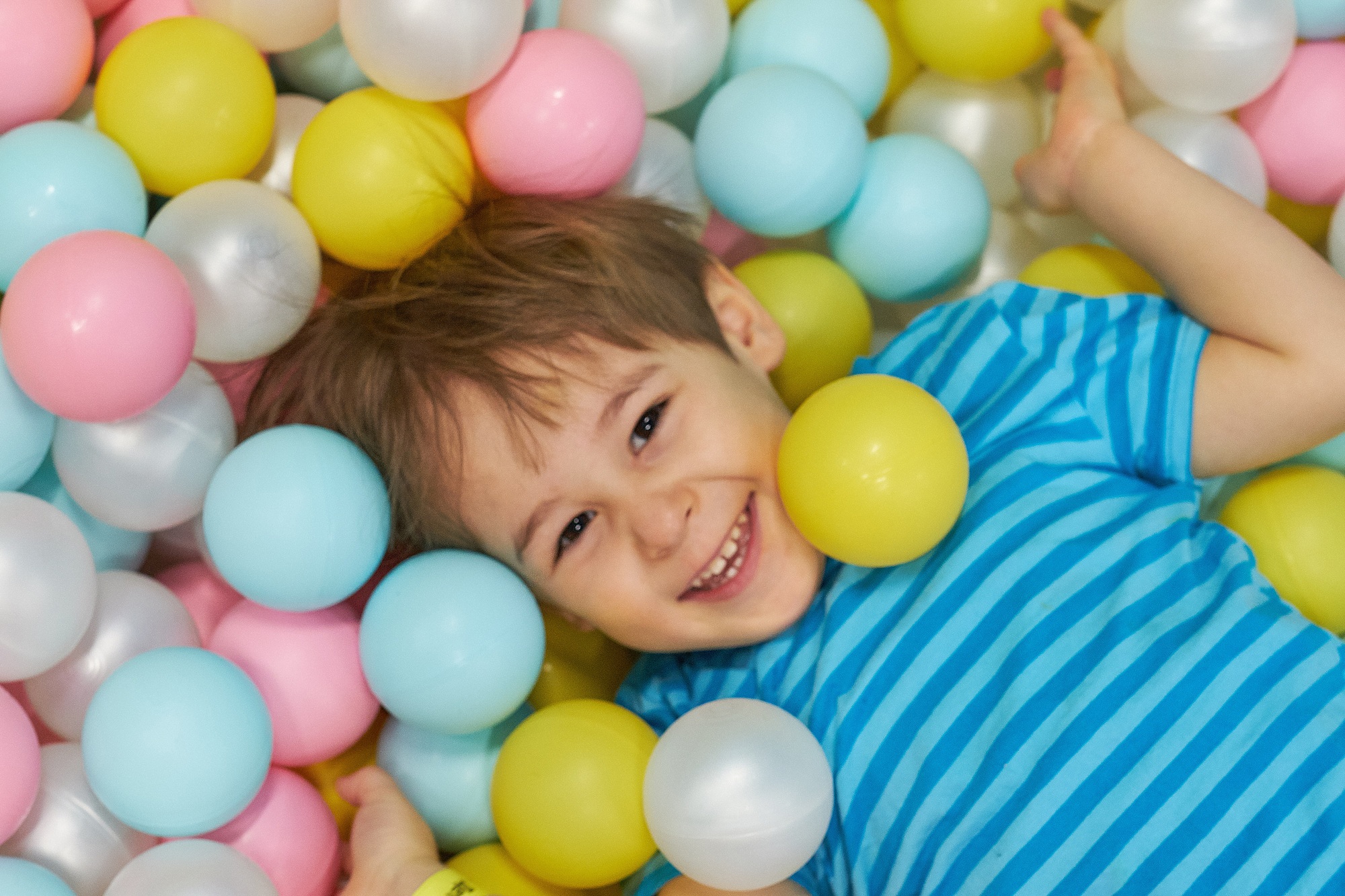 child of three years old is playing in a ball pool.