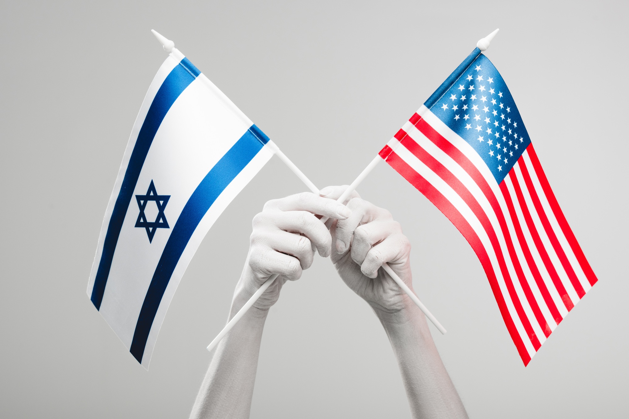 cropped view of female hands painted in white holding crossed american and israel flags isolated on