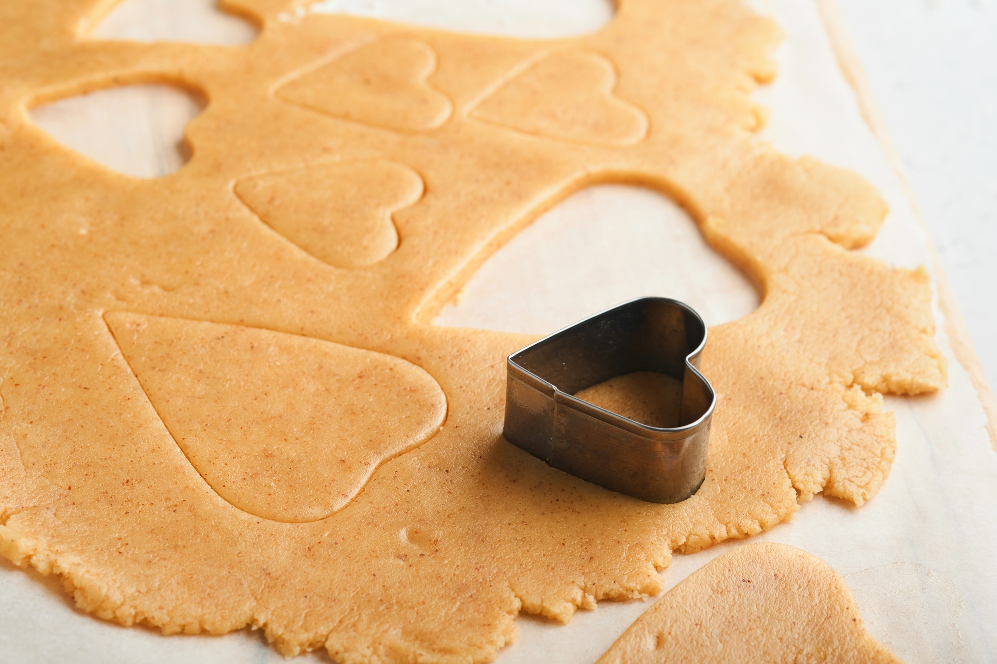 Baking ingredients and kitchen utensils on a white background top view. Preparing heart sugar cookie