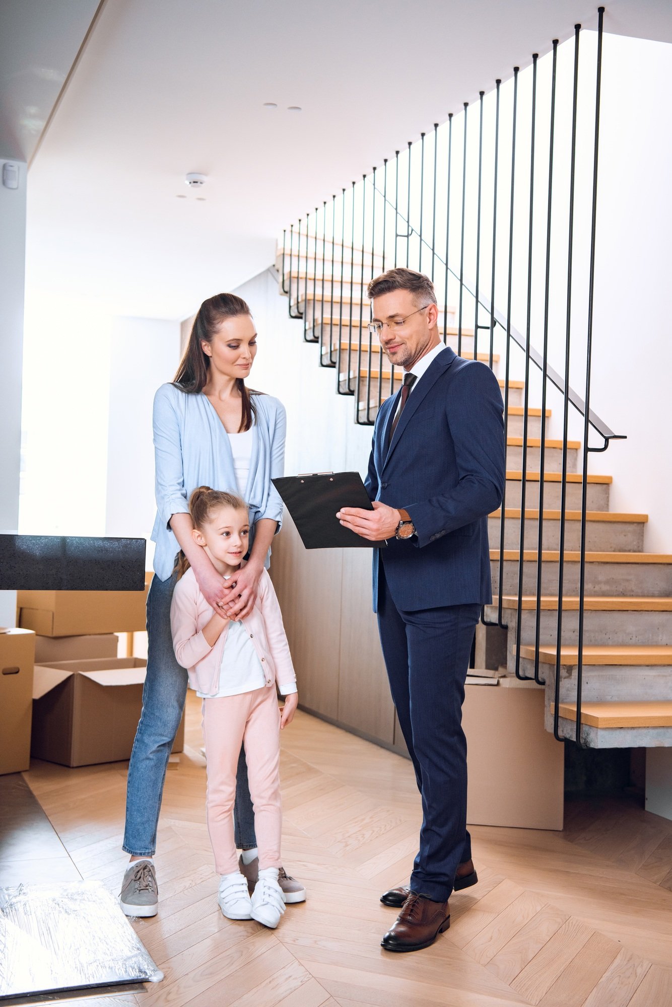 handsome broker holding clipboard and standing near attractive woman with daughter