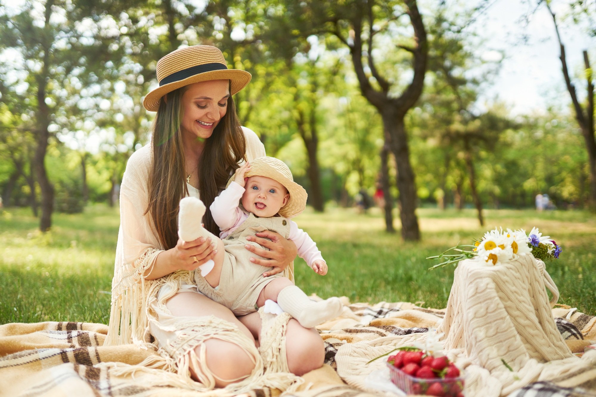 Happy harmonious family outdoors dressed in cool hats. mother with her baby have fan. summer evening