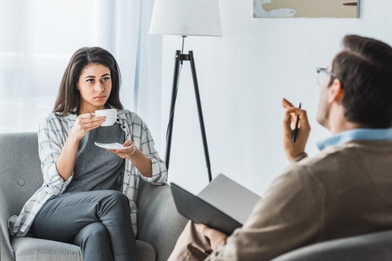 Woman drinking coffee and listening to male doctor recommendations