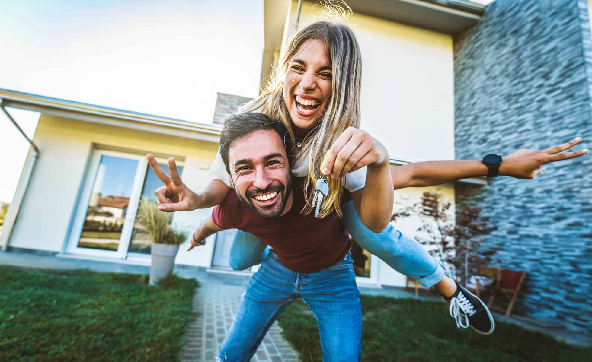 Happy young couple holding home keys after buying real estate