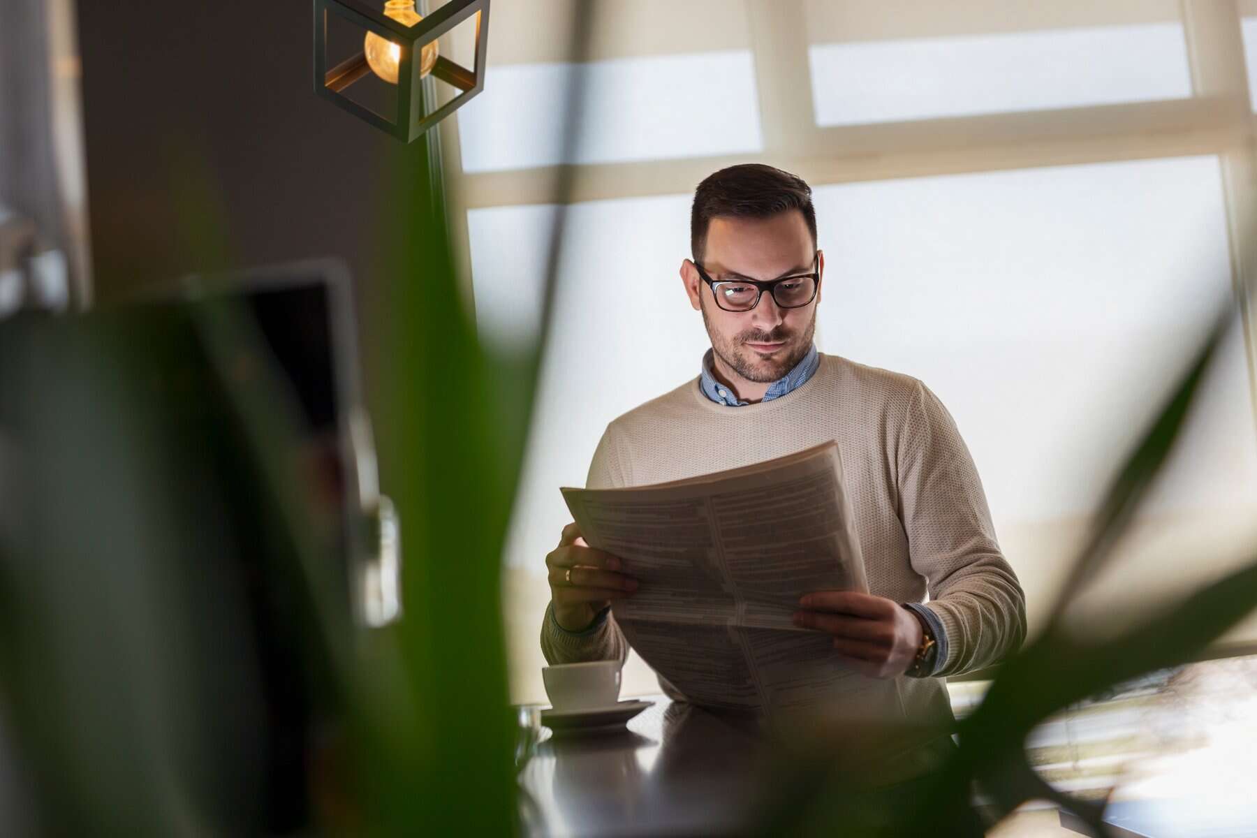 Man reading newspapers and drinking coffee