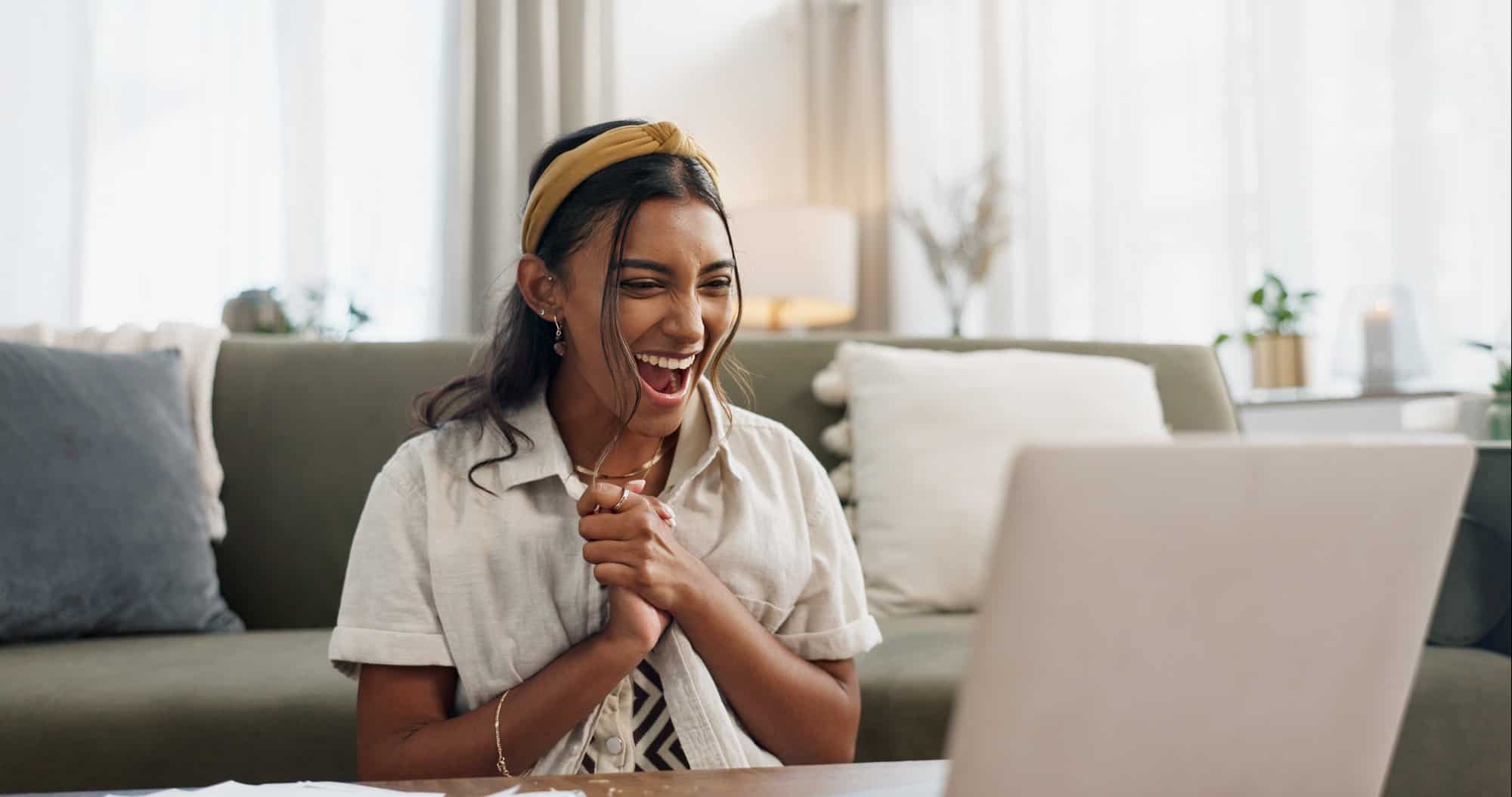 Woman, excited and winning with laptop in home living room on floor with smile, success and profit