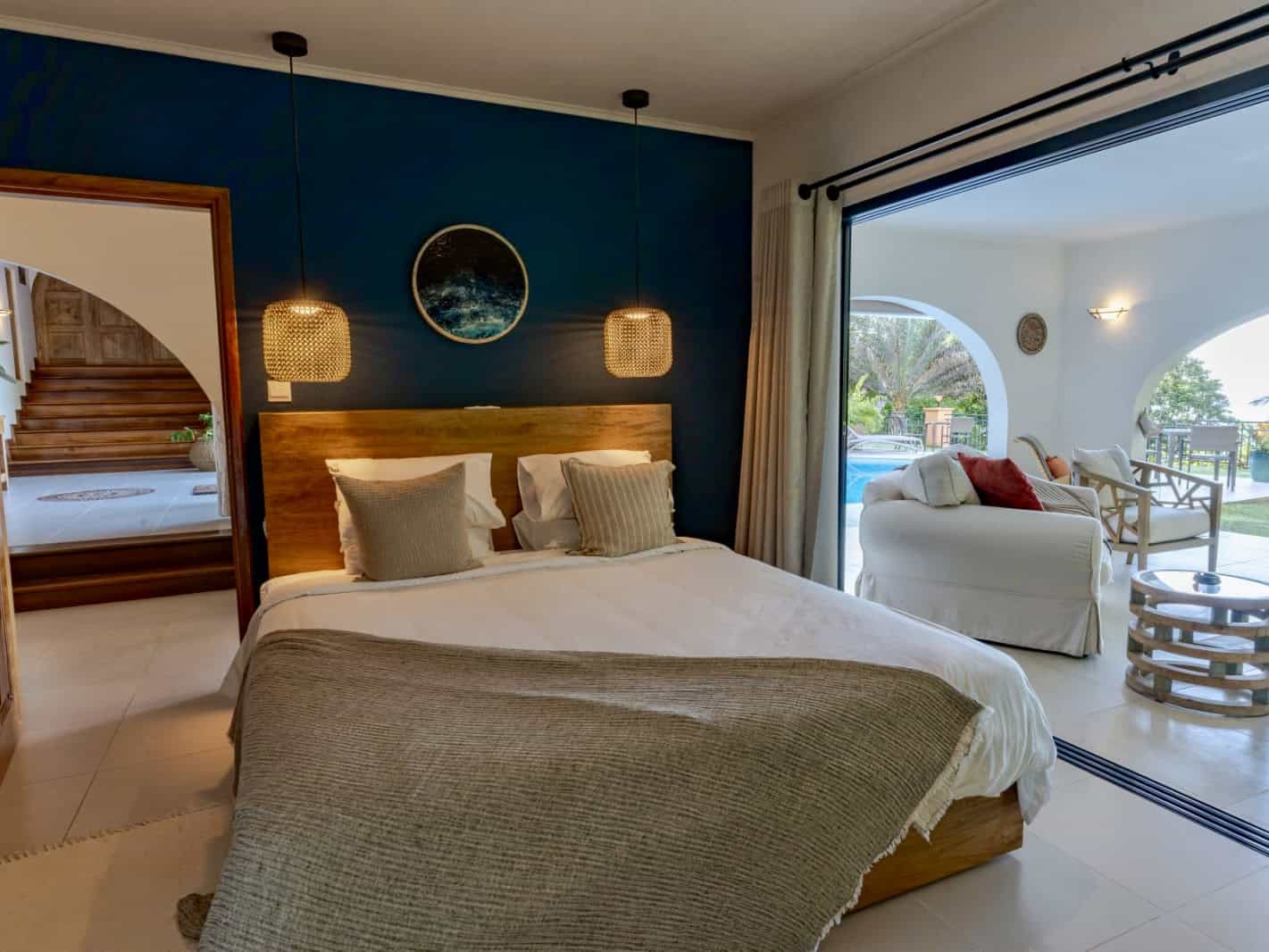 Luminaire suspendue dans chambre élégante avec vue sur terrasse extérieure et piscine en Seychelles.