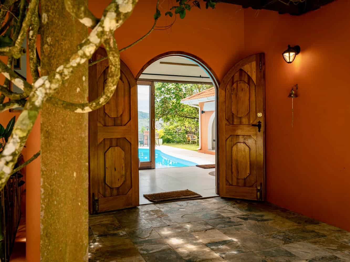 Portes en bois ouvertes donnant sur la terrasse avec piscine à Mahé, Seychelles, ambiance chaleureuse et authentique.
